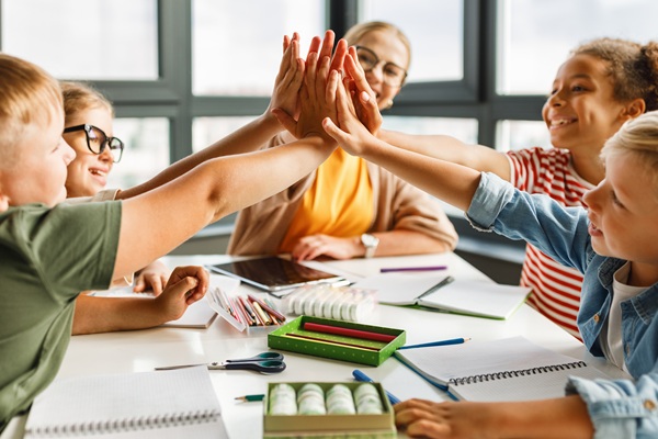 Educator celebrating with students at table in classroom